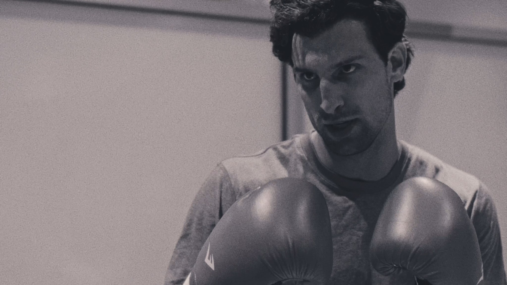 A man wearing boxing gloves looks toward the camera.